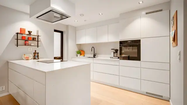 Stilren kjøkkeninnredning med tidløst og moderne uttrykk, benkeplate i stein, og integrerte hvitevarer.