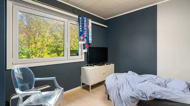 Soverommet har store vinduer med utsyn mot grøntområder